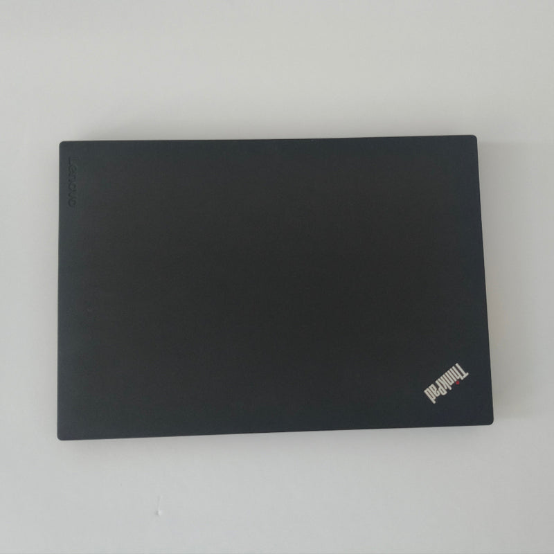 Black lenovo thinkpad laptop on a white surface with a white wall background